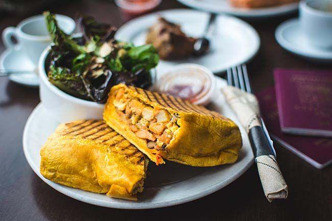 Filling breakfast burrito with salad in a coffeeshop