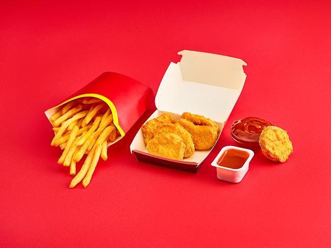 The chicken nuggets and french fries on red background