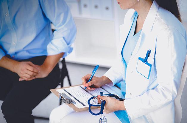 Doctor woman sitting with male patient at the desk .