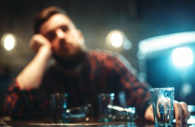 blurred view of man behind empty shot glasses