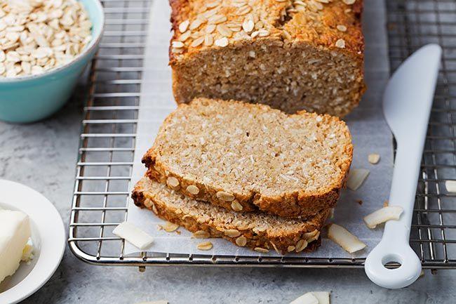 Healthy, gluten-free, vegan oat and coconut loaf bread on a cooling rack. Grey stone background