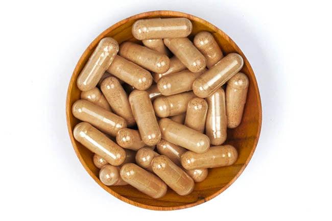 tan herbal supplement in a wooden bowl