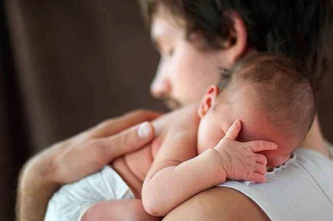 Little newborn is sleeping on fathers arm, covering eyes