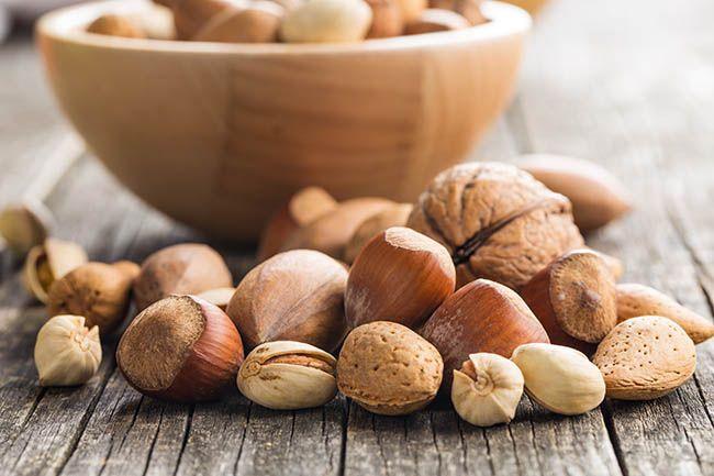 Different types of nuts in the nutshell. Phytates, Hazelnuts, walnuts, almonds, pecan nuts and pistachio nuts on old wooden table.