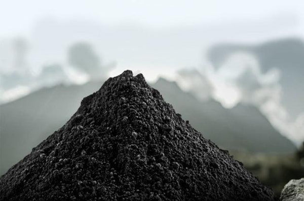 black shilajit powder pile in front of mountain view