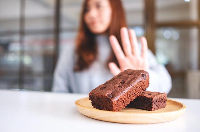 focus view on brownies, blurred background of woman pushing brownies away