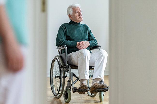 Sad disabled elderly man with parkinsons in wheelchair