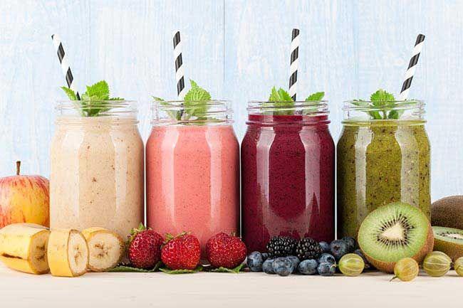 various smoothies, not keeping habit for gut health, fruits and berries on blue wooden background