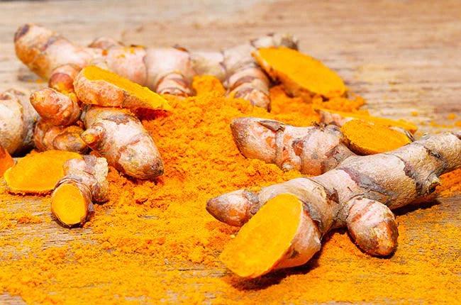 orange turmeric root and powder on wooden background