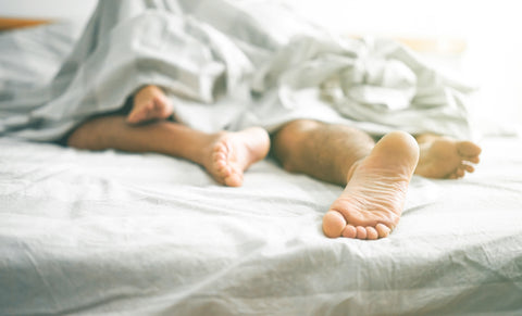 two people connecting their feet in bed
