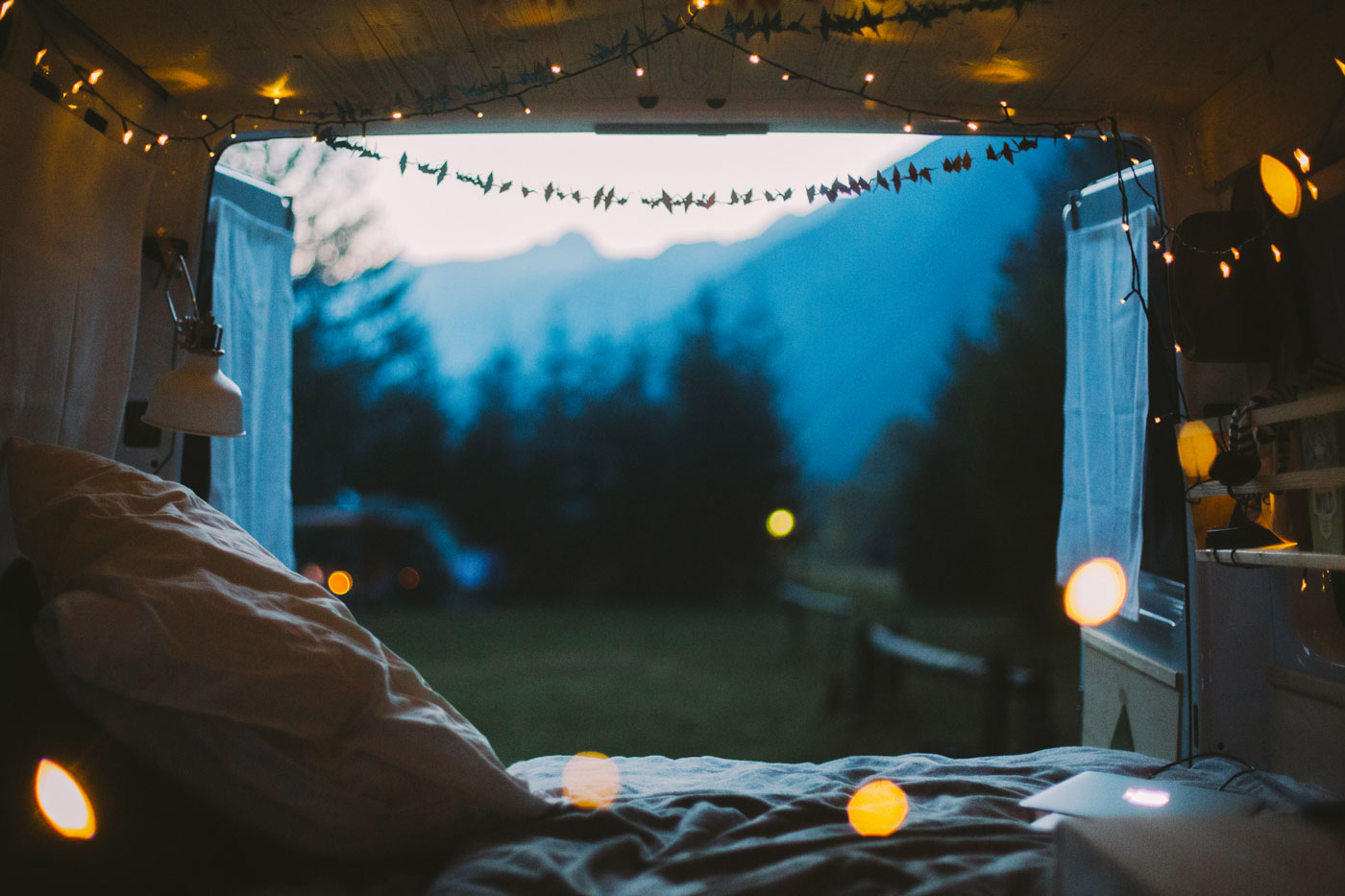 View in to the outdoors from the inside of a van. Little lights hanging from the ceiling of the vehicle. (Photo: Julia Nimke)