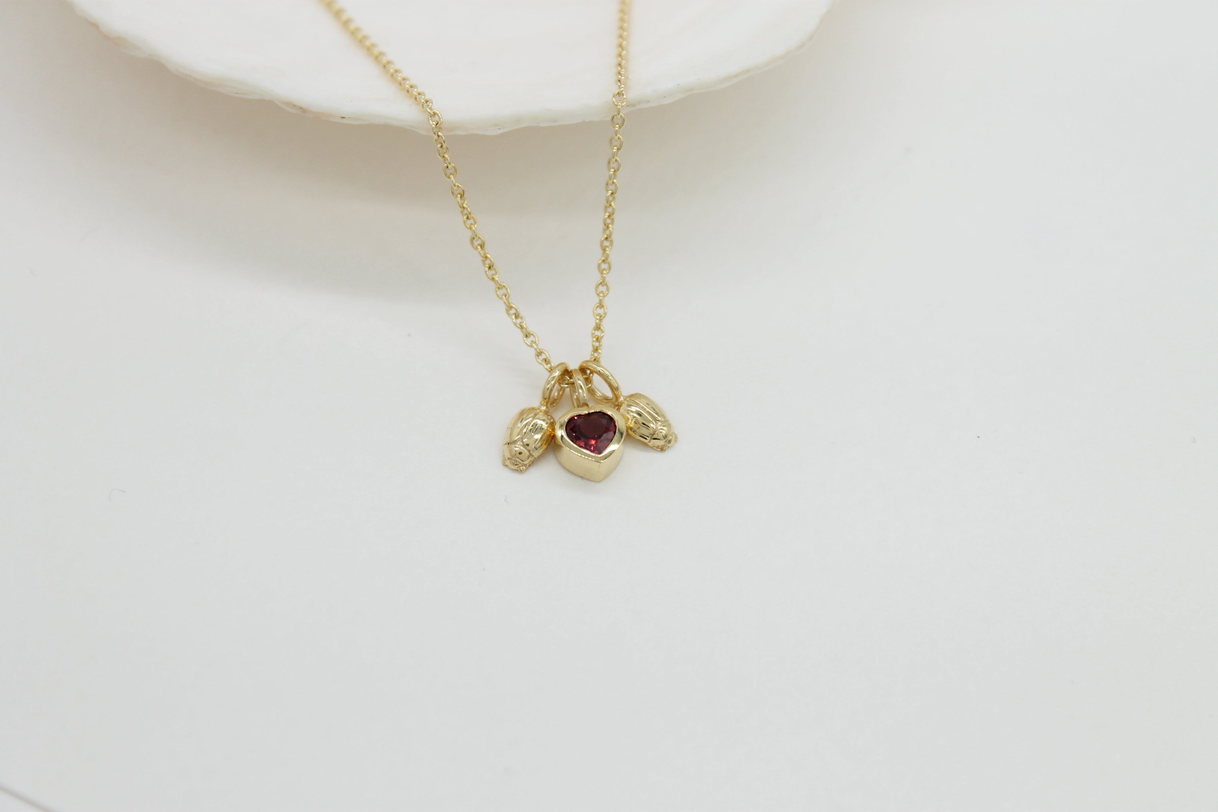 Heart shaped Garnet gemstone set in a gold carm on a gold chain.