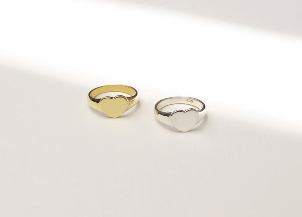 Custom gold and silver signet rings in the shape of a heart.