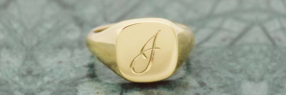 Elegant Aesthetic - Script font engraving on a gold custom signet ring.