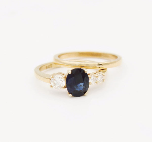 Gold engagement ring with a large sapphire set amongst three smaller diamonds.