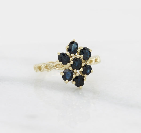 Custom designed and manufactured gold ring with seven sapphires set in a flower shape.