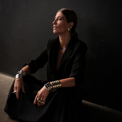 Jovana Djuric seated wearing her signature Horus rings and Embracer cuff bracelets