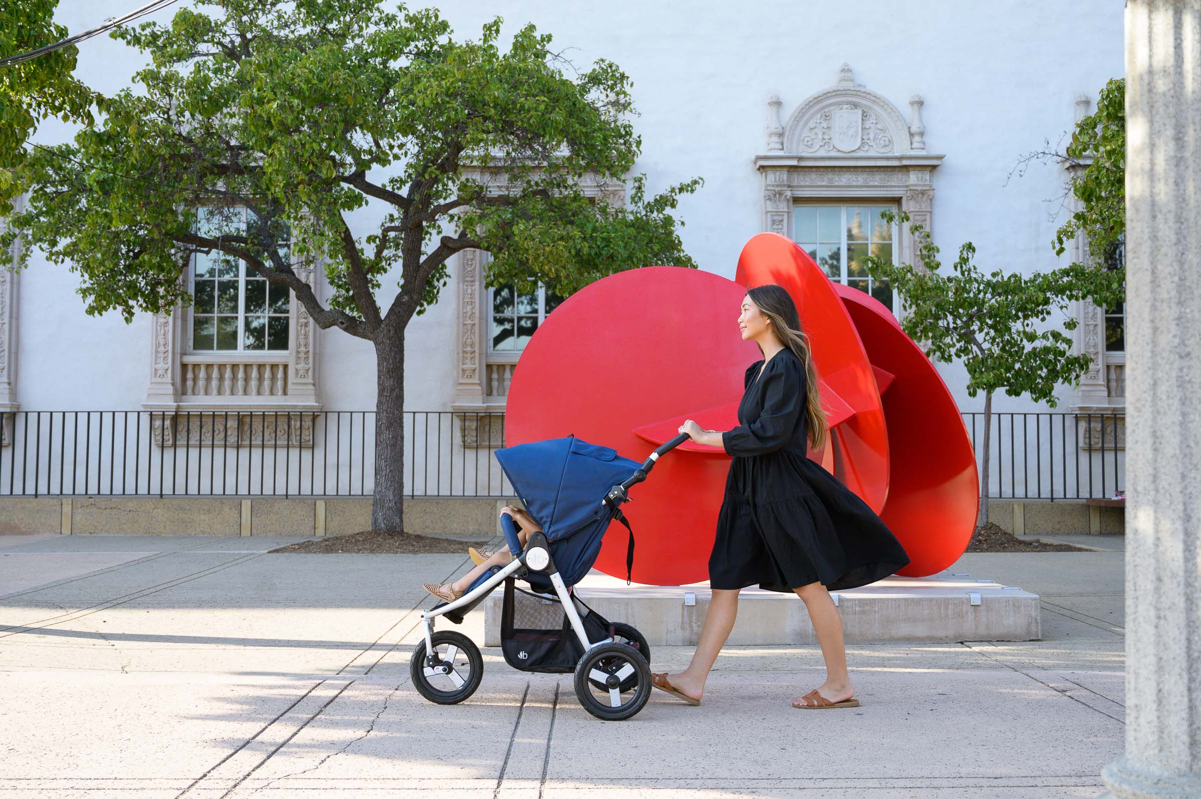 Mother pushing Indie in Maritime Blue in front of large red sculpture in background