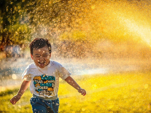 child playing water sprinklers