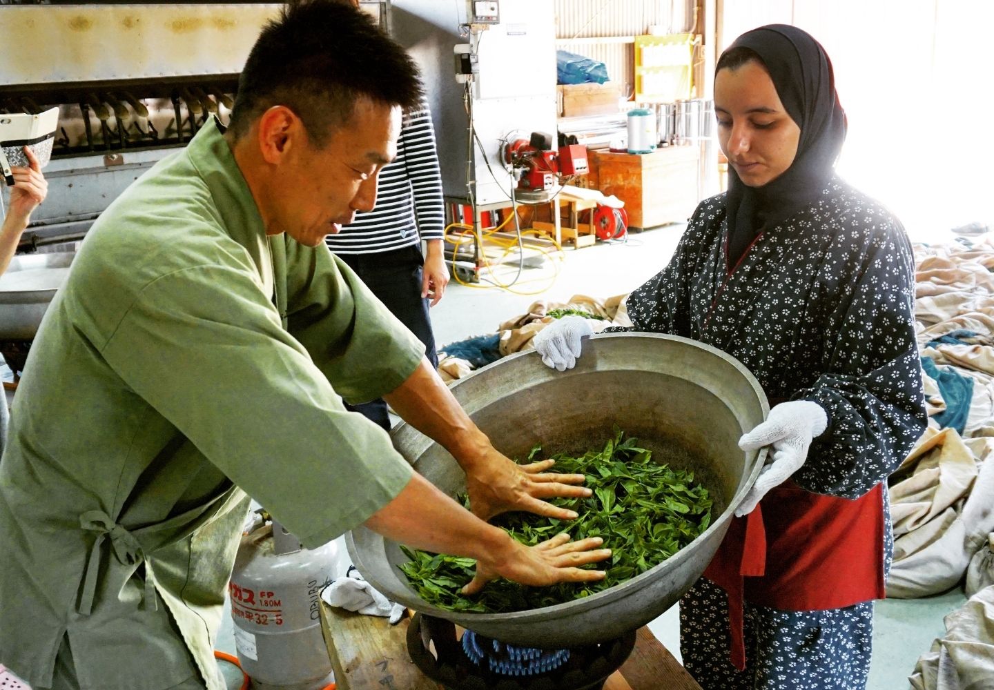 A photo showing two people panning some tea leaves.
