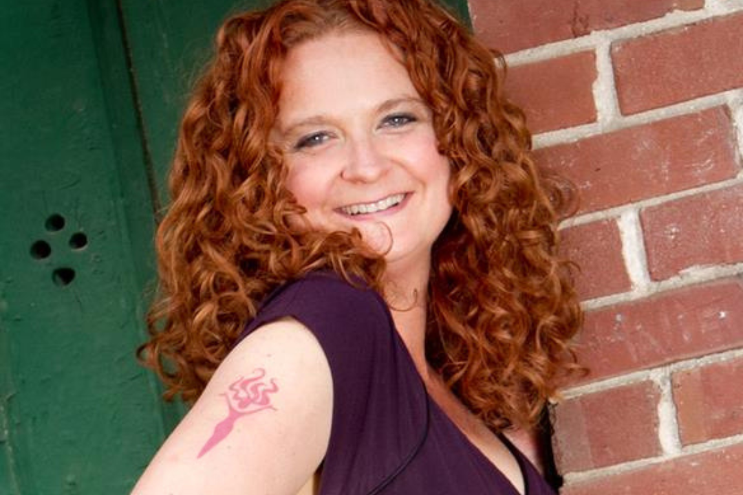 Jess smiling with her "full body logo lady" tattoo visible on her upper arm