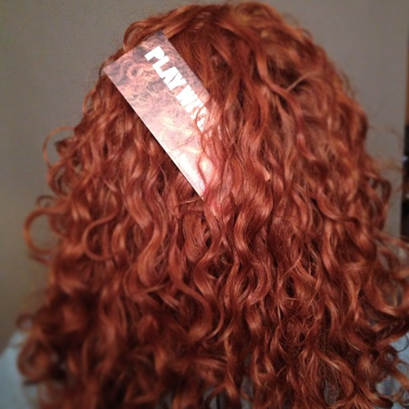 back of red curly haired woman's head with a bookmark in her hair