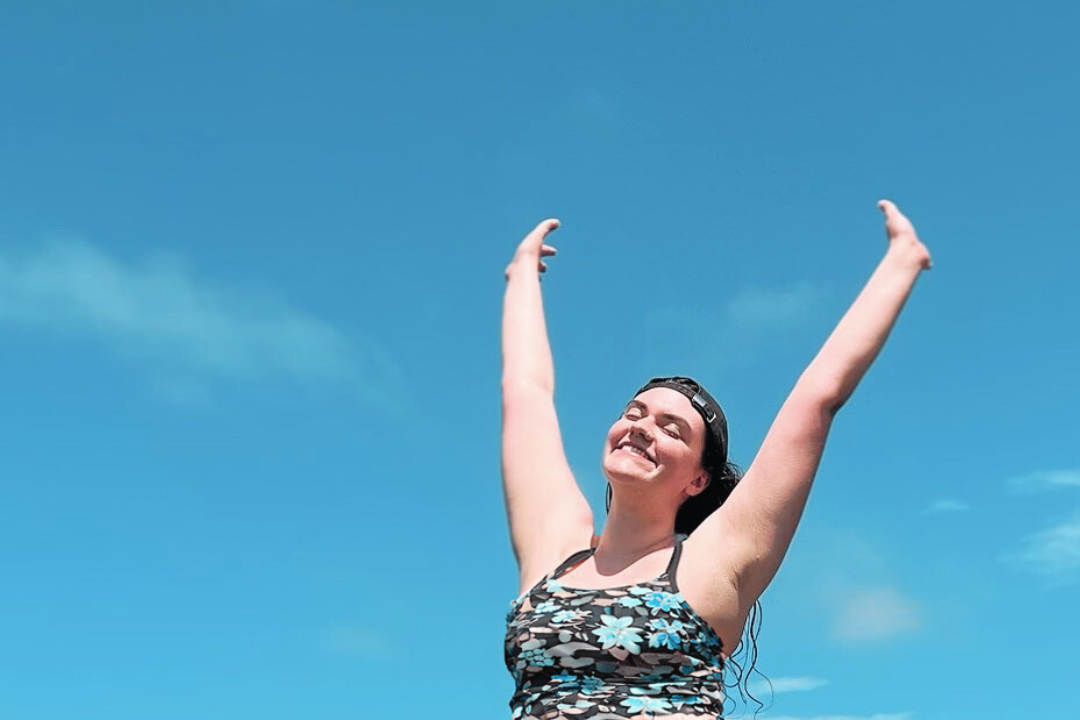woman smiling and raising her hands to the sky