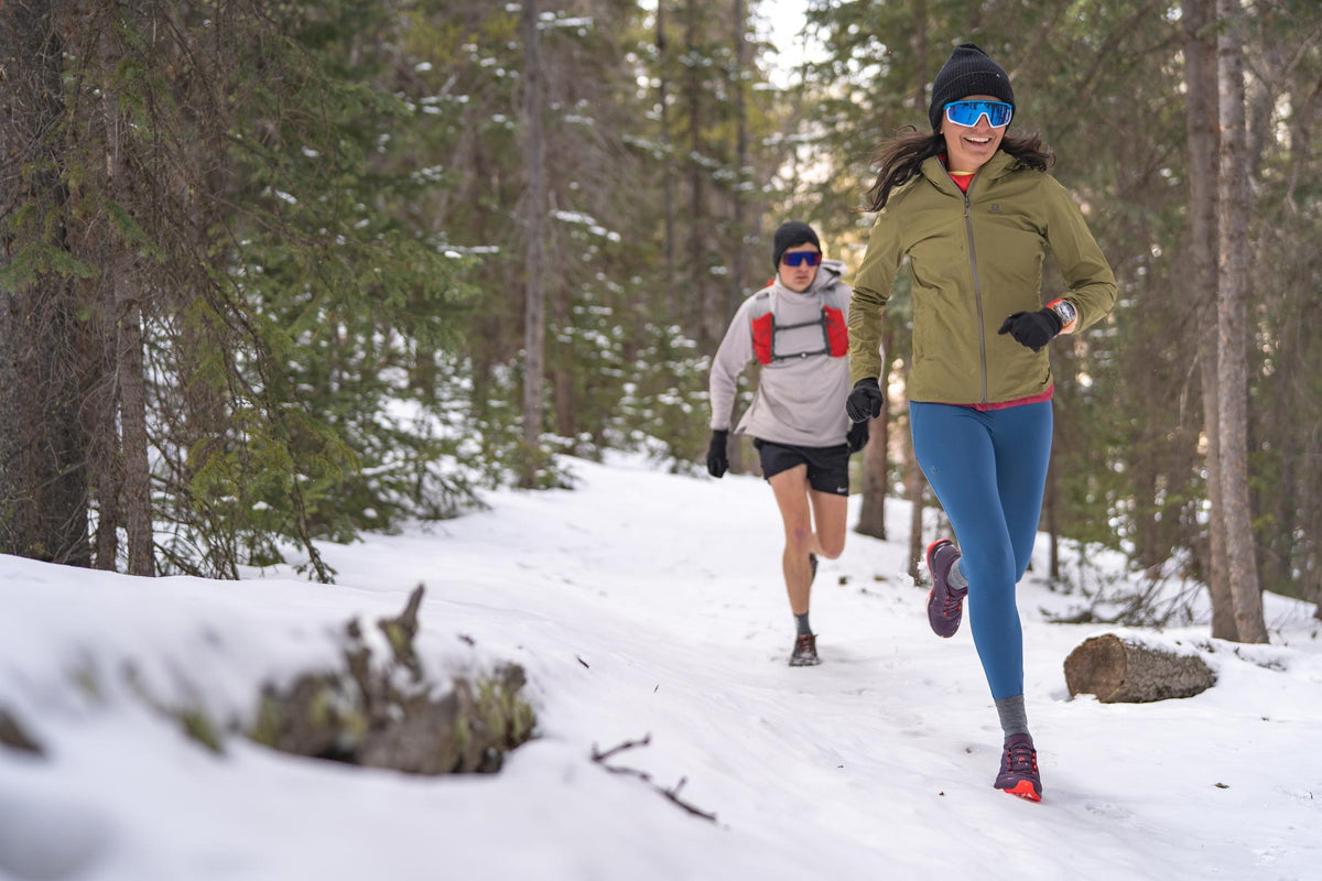 Woman running on trail and stepping in puddle.