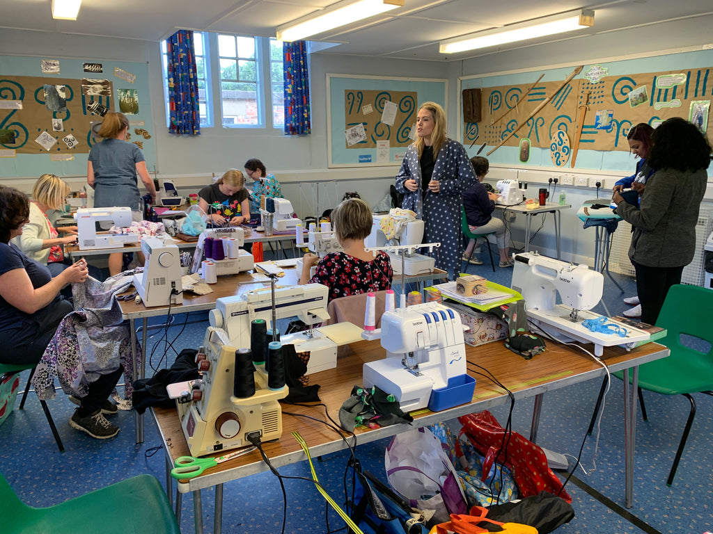 A room full of sewing machines and people talking