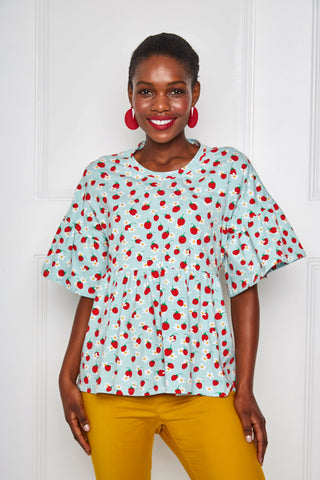 a beautiful black woman modeling our latest pattern, a peplum top with a frill sleeve