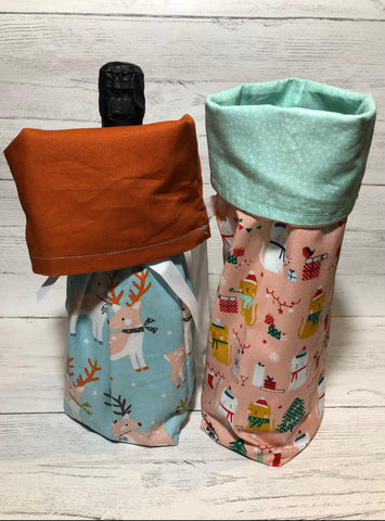 two wine bottle bags made from fabric and tied with a ribbon