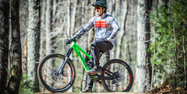 Mountain biker resting on bike seat wearing charcoal Troy Lee Designs Skyline Trousers