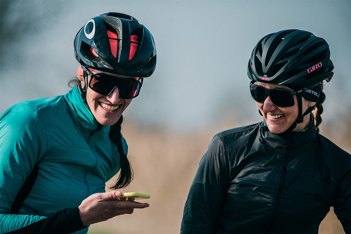 Two female cyclists looking at phone wearing Castelli Pro Thermal Headband