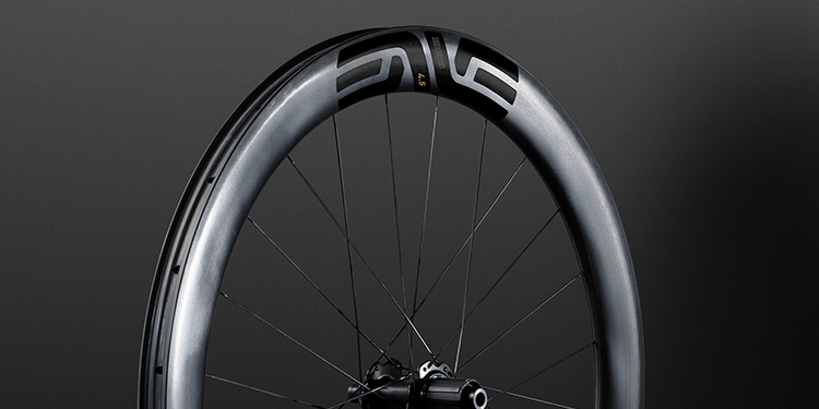 Hero shot of the shiny top three quarters of an ENVE SES 4.5 wheel against a deep grey background