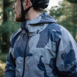 Head and shoulders shot of cyclist in woods looking to the side wearing a Troy Lee Designs Camo Carbon Descent Jacket