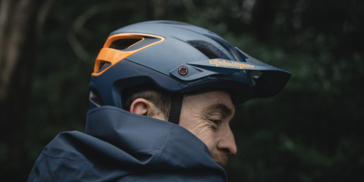 Mountain biker head and shoulders shot, wearing an orange and grey Troy Lee Designs A3 Helmet