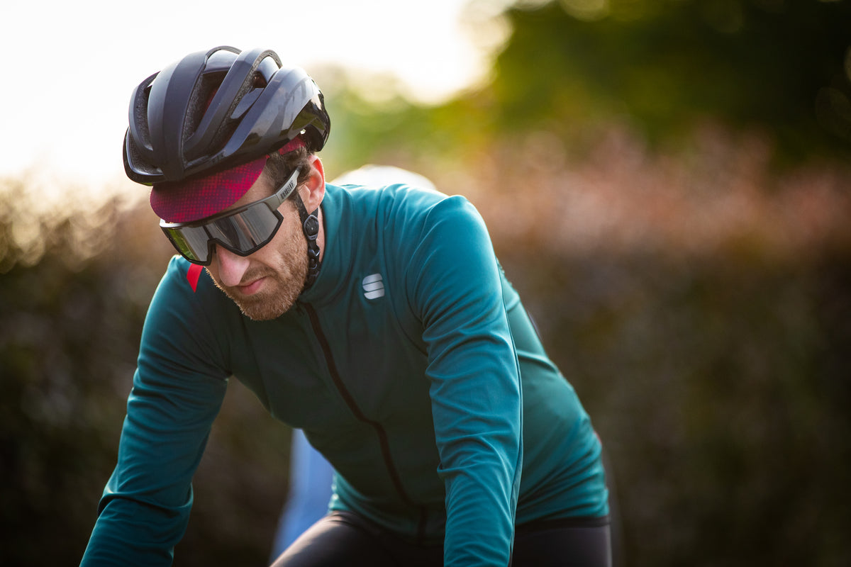 Male cyclist in Sportful winter kit cycles through corn field