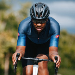 Image of male cyclist in blue Castelli Gabba jacket silhouetted facing forwards against the sea