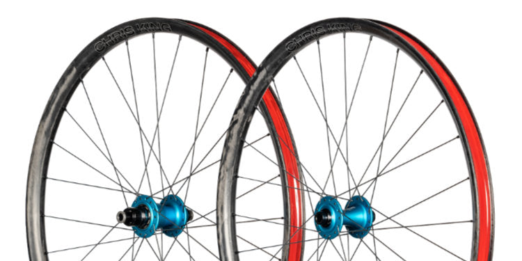 A side on studio shot of a Chris King wheelset with blue King hub and red tape