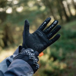 Closeup of hands of cyclist in woods who is adjusting black Troy Lee Designs Gambit Gloves