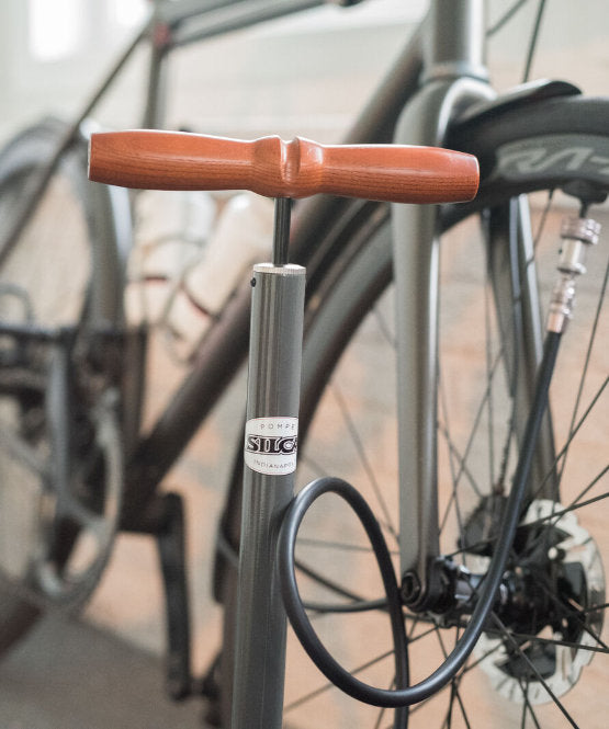 Metal Silca Pista Plus Floor pump with wooden handle attached to a bike in the workshop