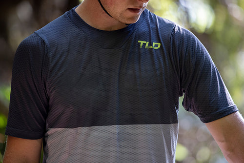 Model wearing the Troy Lee Designs Skyline Air Short Sleeve Jersey in blue and grey with a neon green TLD logo