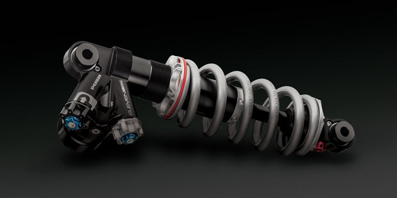 Studio shot of a PUSH ElevenSix Rear Shock from the side against a deep grey background