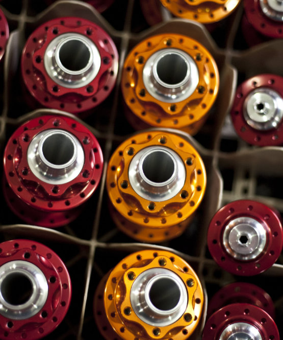 A closeup view of shelves full of yellow and red Chris King hubs