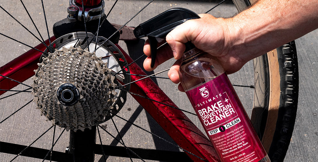 Closeup showing hand spraying Silca Brake and Drivetrain Cleaner on the drivetrain of a red bike
