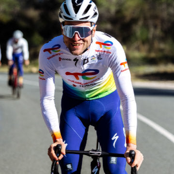 Smiling Team TotalEnergies rider coasting downhill wearing Sportful team branded bib tights and long sleeved jersey