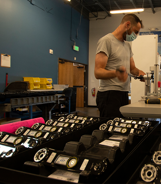 A male worker at Stages Cycling works on a power meter in a vice with complete power meters arranged in the foreground