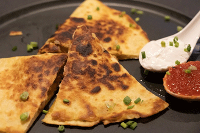 pieces of cut-up quesadilla on black plate