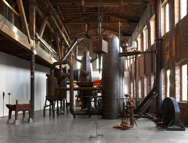 Artistic industrial interior with wooden sculptures, metallic elements, and rustic charm in a loft space.