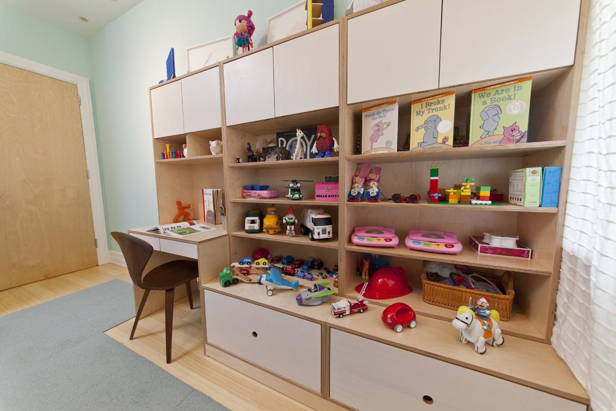 Playful child's room with a study desk, large toy storage shelves, and a soft blue carpet